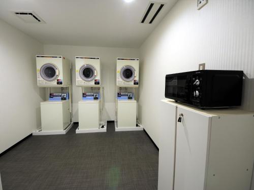 a laundry room with three dryers and a tv at Green Rich Hotel Tottori Ekimae (Artificial hot spring Futamata Yunohana) in Tottori
