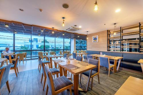a restaurant with wooden tables and chairs and windows at PLAAI Prime Hotel Rayong SHA Extra Plus in Rayong