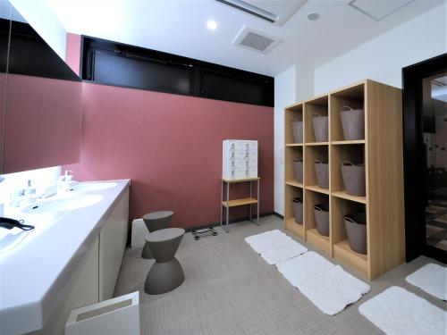 a bathroom with a white sink and a red wall at Green Rich Hotel Tottori Ekimae (Artificial hot spring Futamata Yunohana) in Tottori