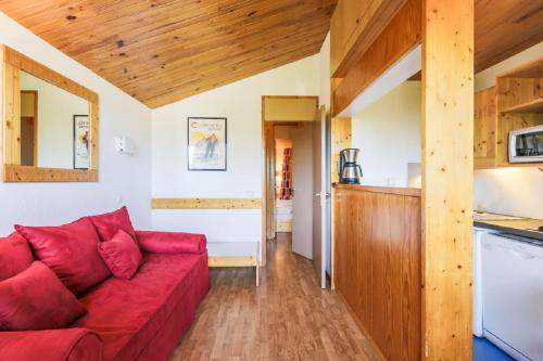 un salon avec un canapé rouge et une cuisine dans l'établissement Residence Les Brigues - maeva Home, à Courchevel
