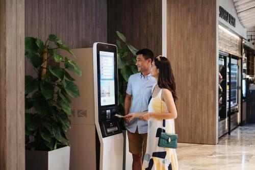 a man and a woman standing next to a machine at Village Hotel Sentosa by Far East Hospitality in Singapore