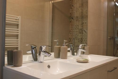 a bathroom sink with two faucets and a mirror at LES BOIS DE CHAMPAGNE NORDIQUE in Magnant