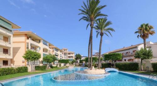 a swimming pool with palm trees and buildings at Studio Parque Mar in La Mata