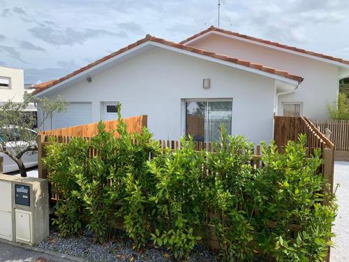 una casa blanca con una valla y arbustos en Chambre privée avec terrasse, en Capbreton