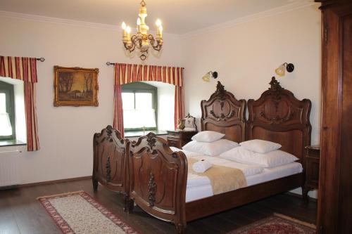 Un dormitorio con una gran cama de madera con almohadas blancas. en Edvy Malom Fogadó Barokk Udvarház en Pápa