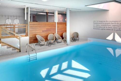a swimming pool in a room with chairs around it at Hôtel Au Chamois d'Or by Les Etincelles in L'Alpe-d'Huez