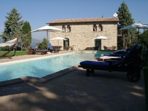 a swimming pool with chairs and a house with a building at Podere Caldaruccio La Pineta in Bosco