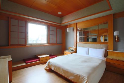 a bedroom with a large bed and a window at Hua Du Hotel in Keelung