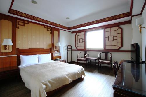 1 dormitorio con 1 cama, mesa y sillas en Hua Du Hotel, en Keelung