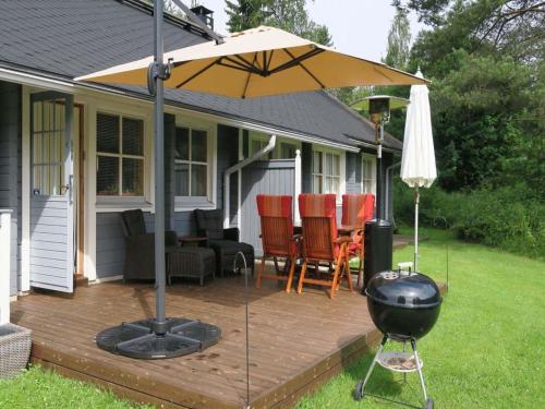 een houten terras met een grill en een parasol bij Holiday Home Aaria by Interhome in Tahkovuori