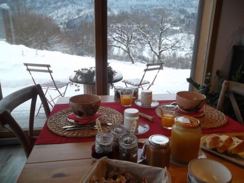 een tafel met eten en uitzicht op een met sneeuw bedekte berg bij La Buissonnière in Le Noyer