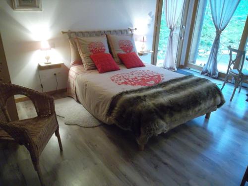 a bedroom with a large bed with red pillows at La Buissonnière in Le Noyer