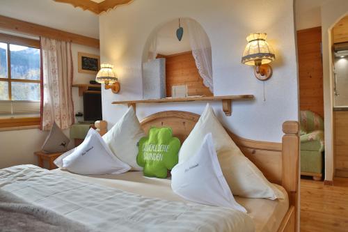 ein Schlafzimmer mit einem Bett mit einem grünen ausgestopften Tier darauf in der Unterkunft Bauernhof Waldesruh in Tannheim