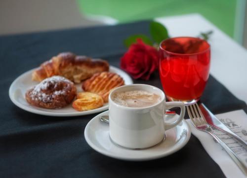 a cup of coffee and a plate of doughnuts and a glass of red drink at Hotel Playa Ribera in Suances