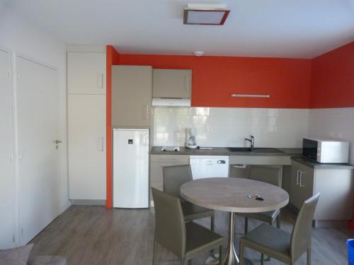 a kitchen with a table and a kitchen with red walls at Résidence Le 101 in Millau