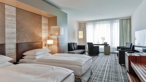 a hotel room with two beds and a desk at Dorint Hotel am Heumarkt Köln in Cologne
