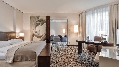 a hotel room with a bed and a desk at Dorint Hotel am Heumarkt Köln in Cologne