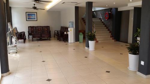 a lobby with a staircase and chairs and a tile floor at Harbour Inn in Melaka