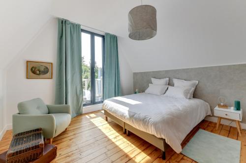 a bedroom with a bed and a chair and a window at Cottage de la Forêt in Chantilly