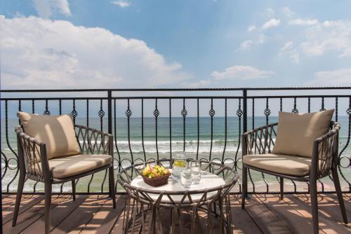 a balcony with two chairs and a table with a bowl of fruit at Effect Algara Beach Resort - Ultra All Inclusive and Free Parking in Kranevo