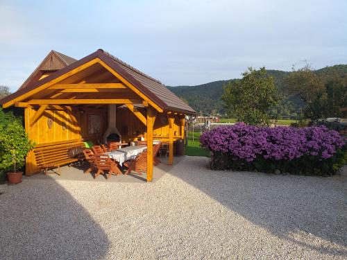 a wooden gazebo with purple flowers in a garden at Penzión Anika in Krásnohorská Dlhá Lúka