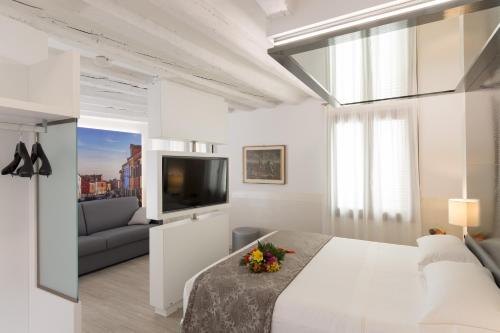 a white bedroom with a large bed and a couch at UNAHOTELS Ala Venezia-Adults 16 in Venice