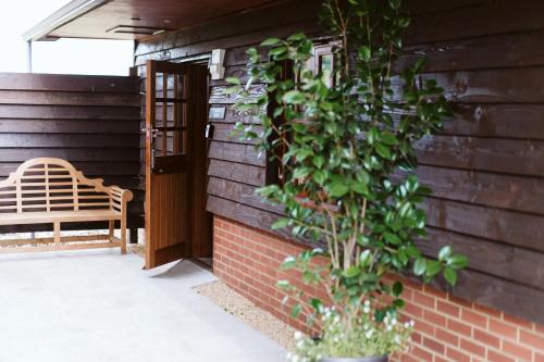 a bench sitting next to a brick building with a plant at The Apple Rooms - Houghton Lodge in Stockbridge