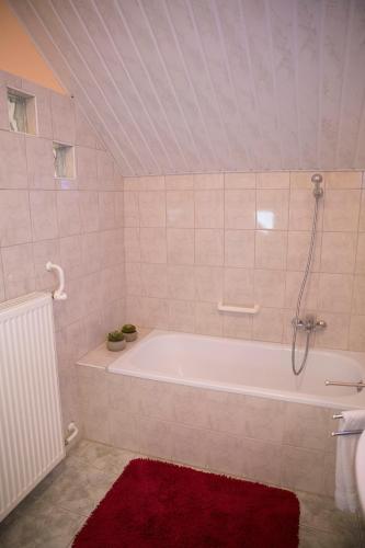a bathroom with a tub and a red rug at Antalóczy Vendégház in Tokaj