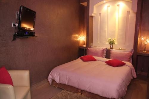 a bedroom with a bed and a tv on a wall at Riad Carllian in Marrakesh