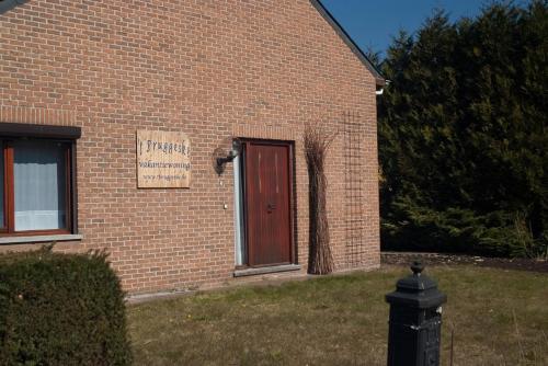 a brick building with a red door and a sign on it at 't Bruggeske in Mol