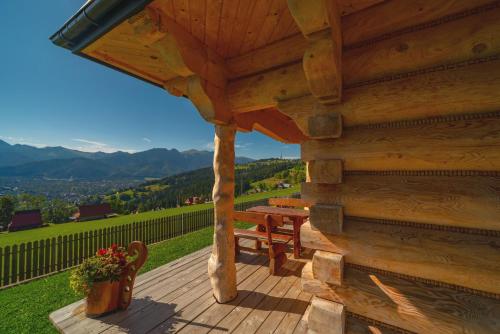 a wooden deck with a bench and a table at Domki na Gubałówce in Zakopane