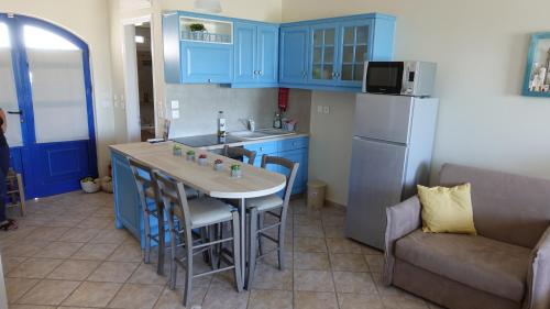 une cuisine avec des placards bleus, une table et un canapé dans l'établissement Sea Urchin Apartments 1st floor, à Agía Pelagía