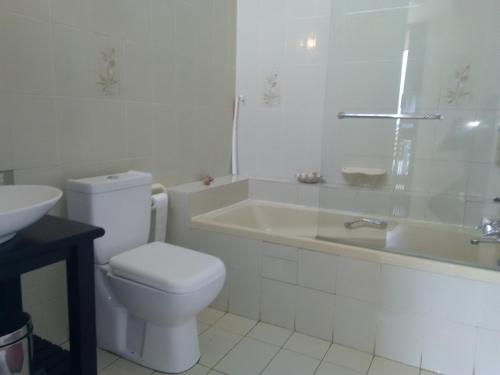 a white bathroom with a toilet and a sink at La-Peng Guest House in La Mercy