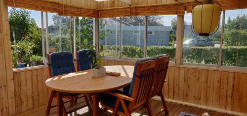 a wooden table and chairs in a room with windows at Family room in Trönninge