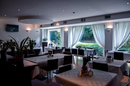 a restaurant with white tables and chairs and large windows at Aston Hotel in Pino Torinese