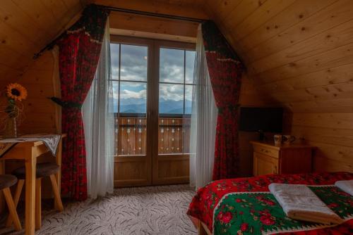 a bedroom with a bed and a large window at Domki na Gubałówce in Zakopane