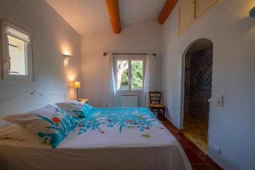 a bedroom with a bed with blue sheets and a window at La Bastide des Vignaux in Grimaud