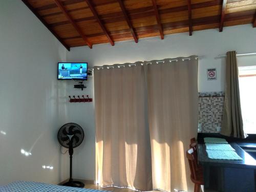 a bedroom with a white curtain and a television on the wall at Chalés Vale dos Pássaros in Paraty