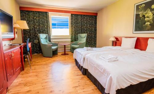 ein Hotelzimmer mit einem Bett, einem Tisch und Stühlen in der Unterkunft Skoogs City BnB in Piteå