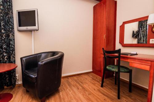 een kamer met een bureau, een stoel en een televisie bij Skoogs City BnB in Piteå