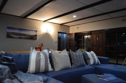 uma sala de estar com um sofá azul com almofadas brancas em Seabatical em Knysna