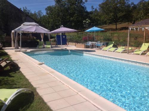 una grande piscina con sedie e ombrelloni di Dordogne Farmhouse a Beaulieu-sur-Dordogne