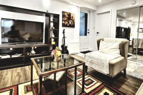 a living room with a television and a chair and a glass table at Cosy apartment at Bossuet road in Montréal