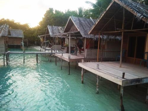 a group of huts in the water next to a pool at Sunset homestay in Besir