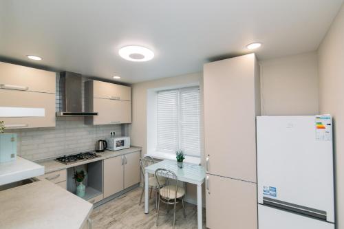a kitchen with a table and a white refrigerator at Luxury Apartment neer Manufaktura on Kharkovskaya in Sumy