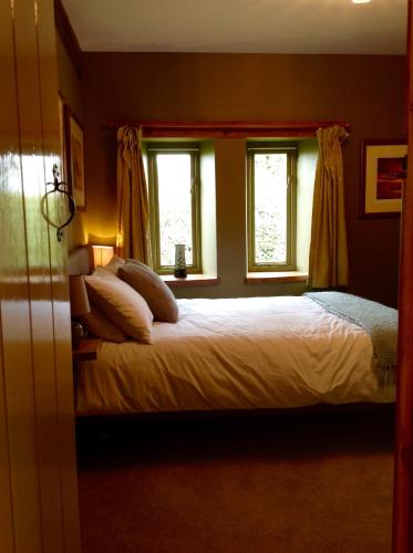 a bedroom with a bed with two pillows and two windows at Chestnut Lodge in East Dereham