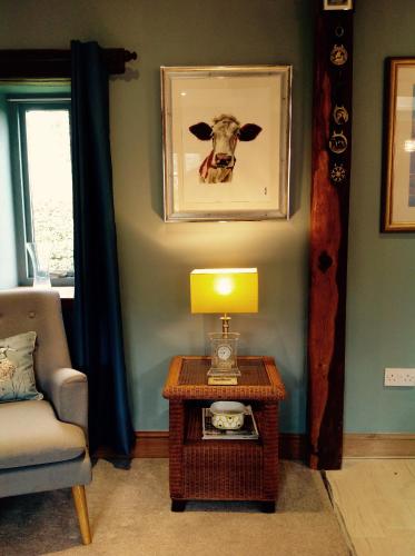 a living room with a table and a picture of a cow on the wall at Chestnut Lodge in East Dereham