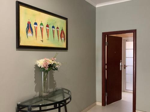 a vase of flowers on a glass table next to a painting at Bannerloft Guest house in Gaborone