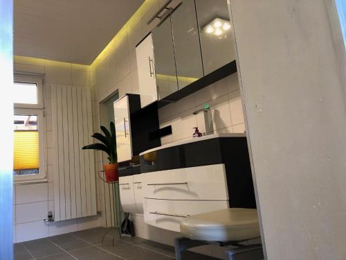 baño con armario blanco y negro y taburete en Ferienwohnung Harzerfuchs, en Wernigerode