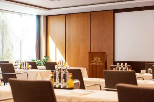 a conference room with tables and chairs and a screen at Hotel Nassauer Hof in Wiesbaden